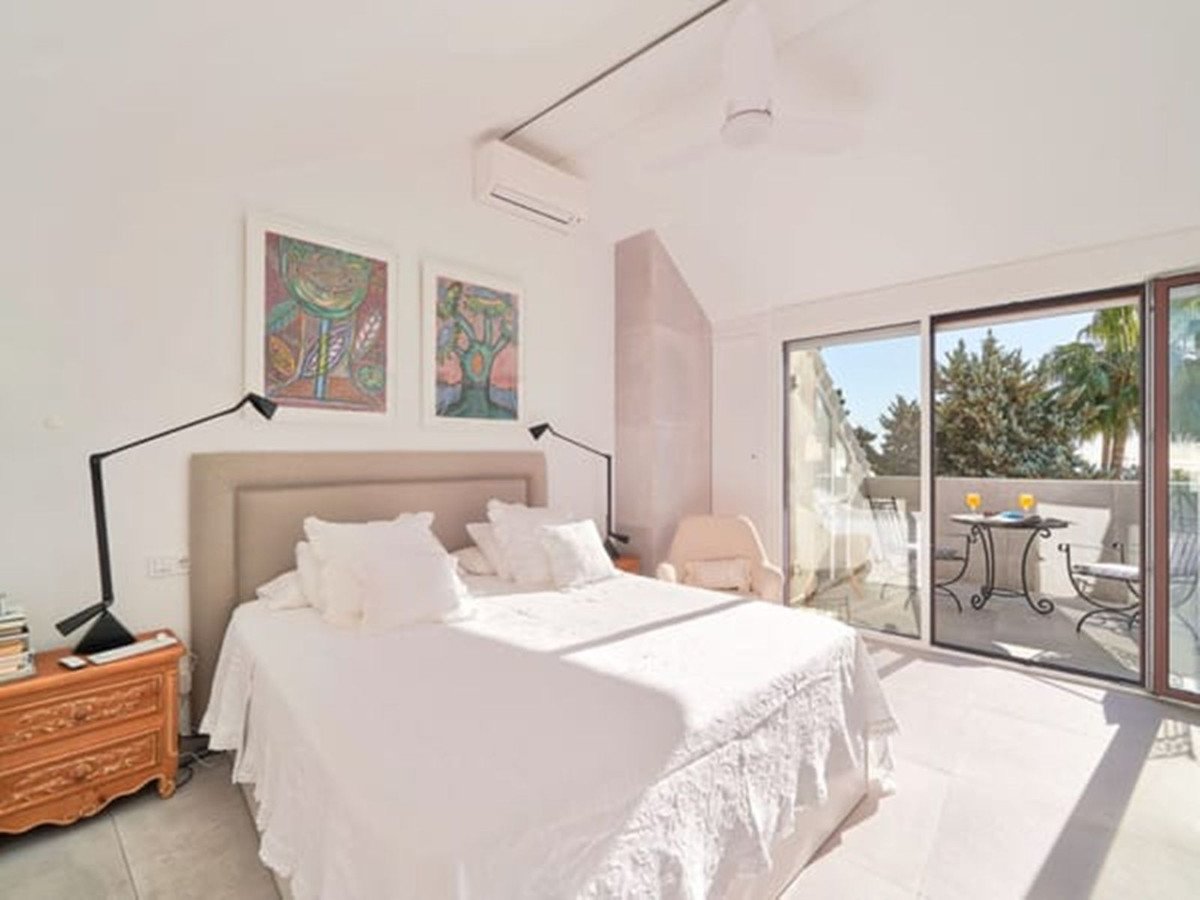 Bright master bedroom with white bedding and sliding glass doors to outdoor balcony
