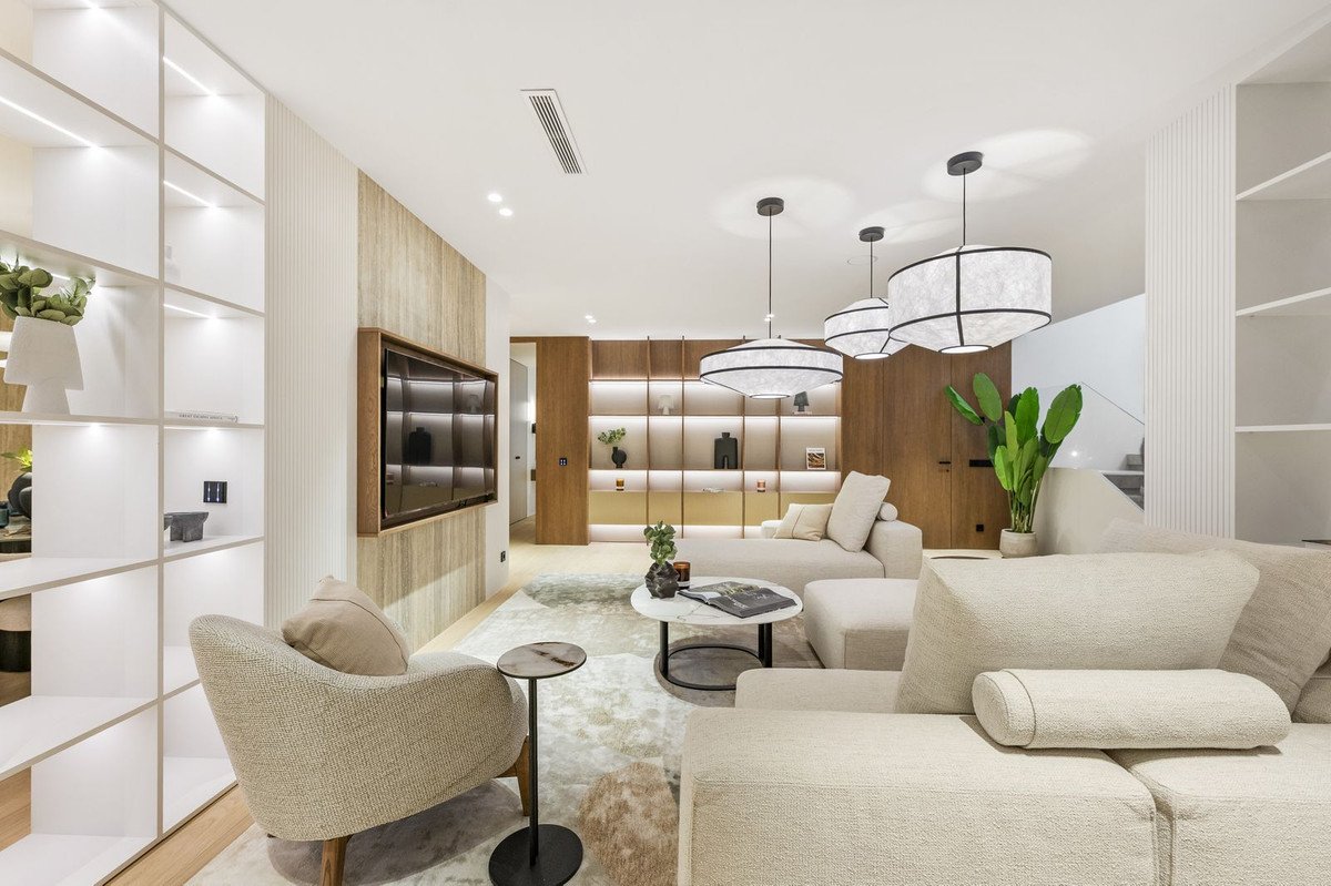 Modern living room with large sectional sofa, built-in shelves, large TV, and stylish pendant lights.