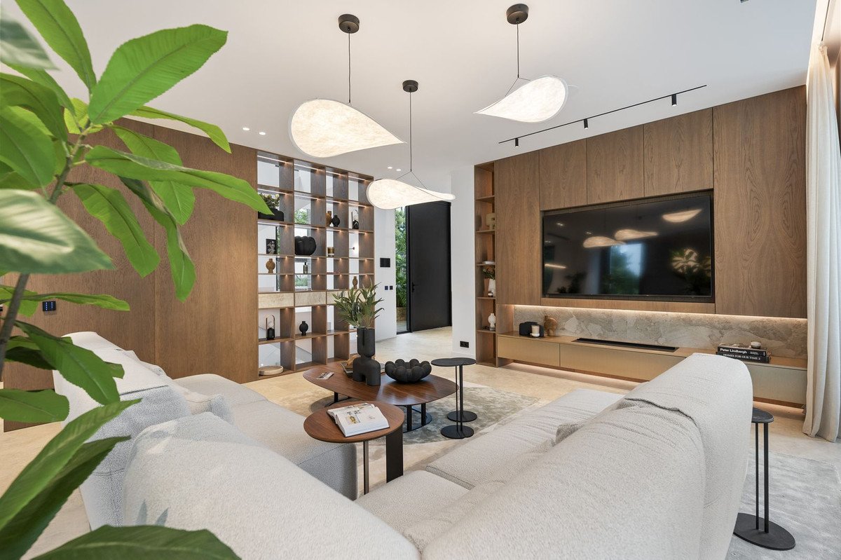 Modern living room with large TV, built-in shelving unit, comfortable sofa, and stylish pendant lighting.