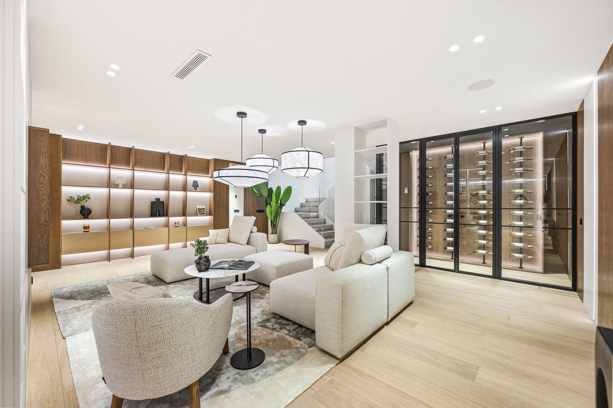 Modern living room with white sofas, glass wine cellar, and built-in shelves