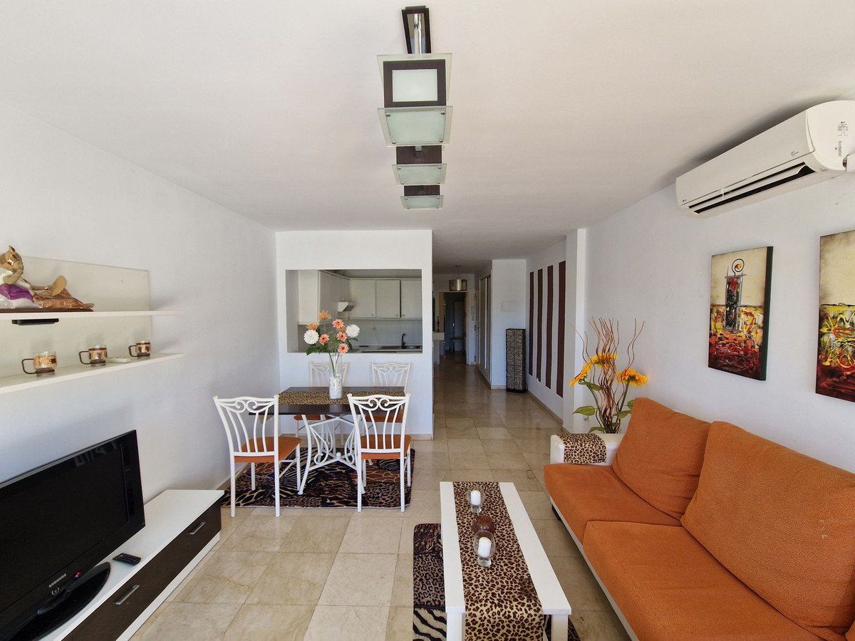 Open-plan living and dining room with orange sofa, white chairs, and modern decor