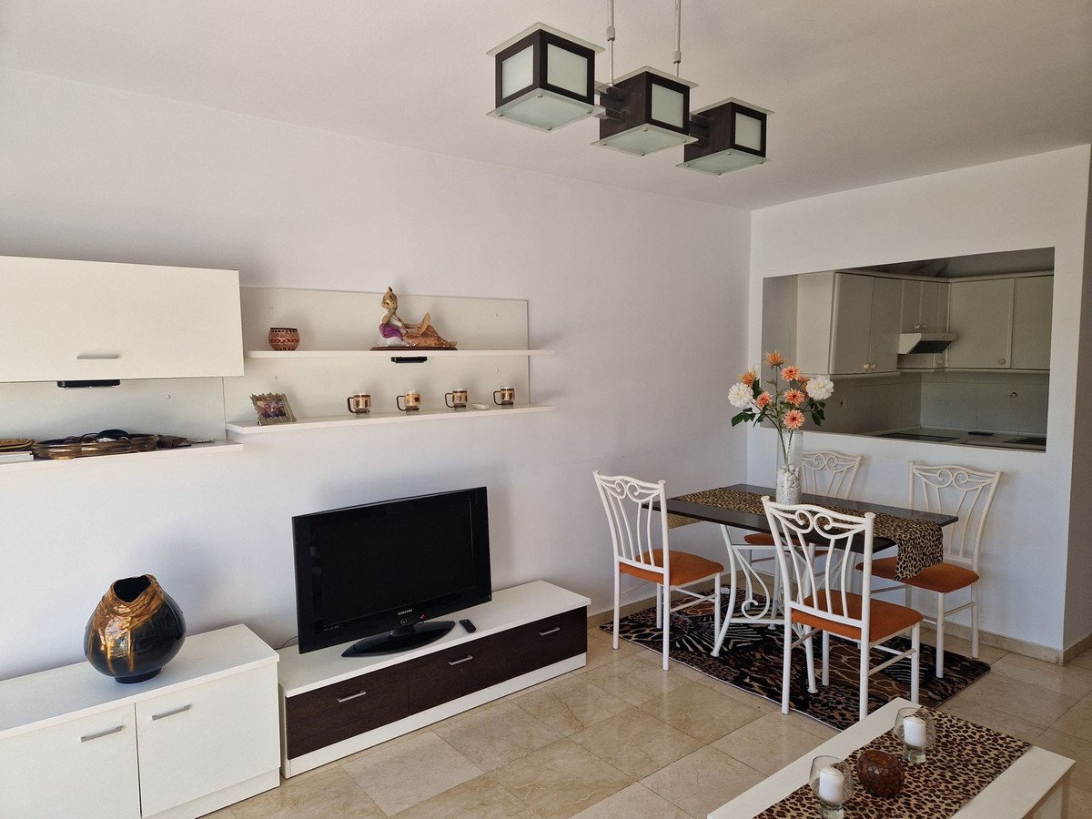 Open-plan living, dining, and kitchen area with white furniture and tiled floors