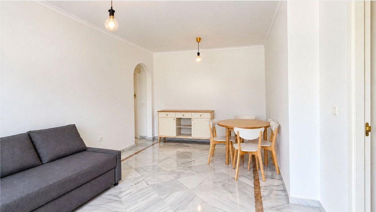 Living and dining room with grey sofa, wooden table, and marble flooring