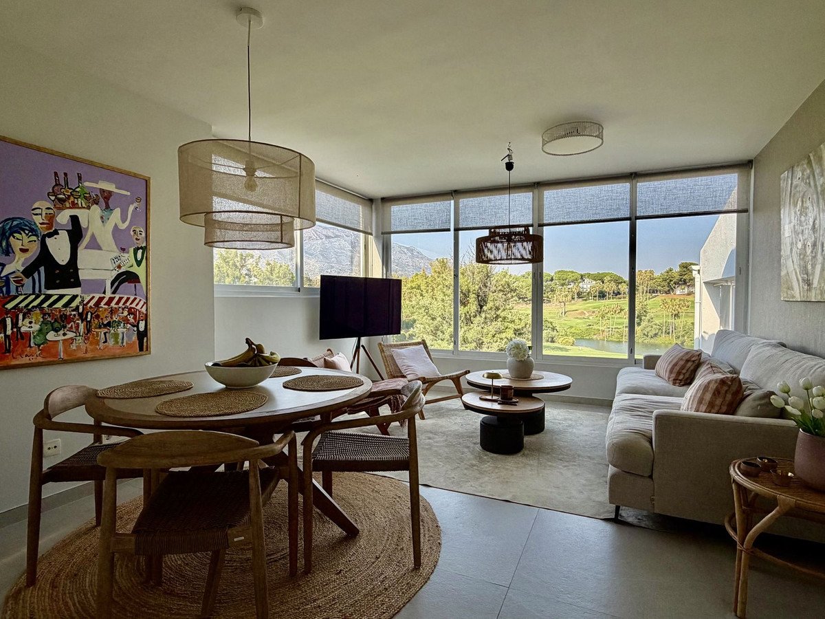 Modern living and dining area with large windows overlooking a golf course and lake.