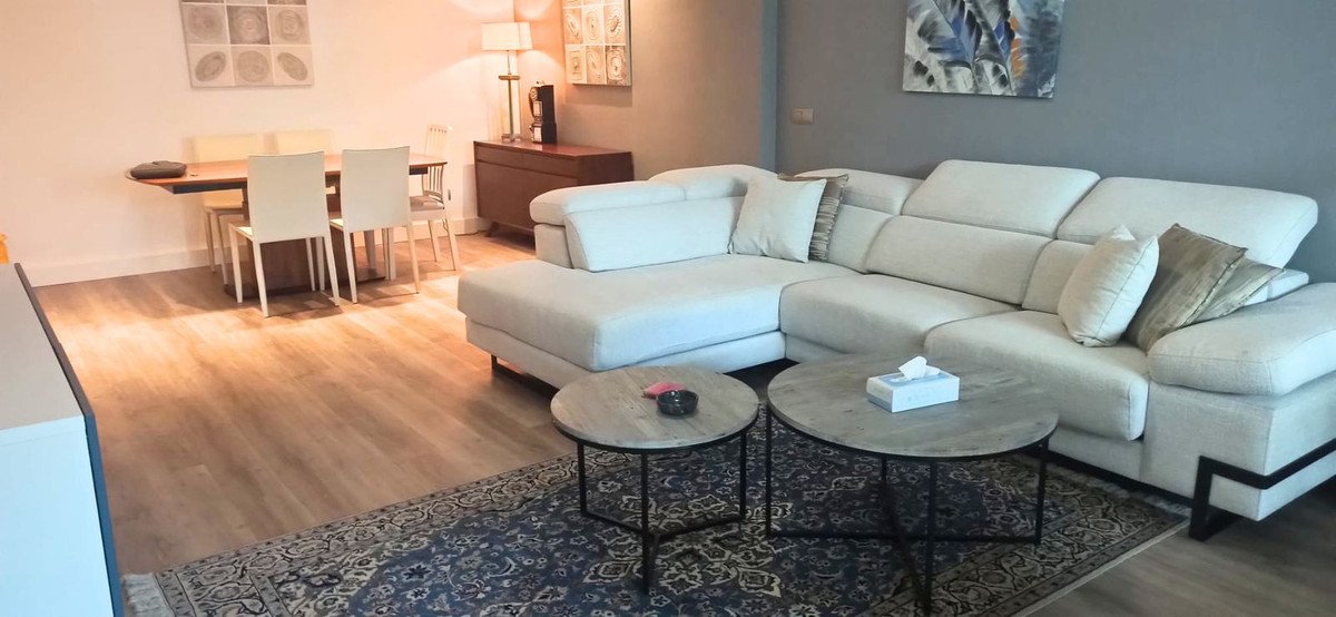 Spacious living and dining area with a large sectional sofa, coffee tables, and a wooden dining set with chairs.