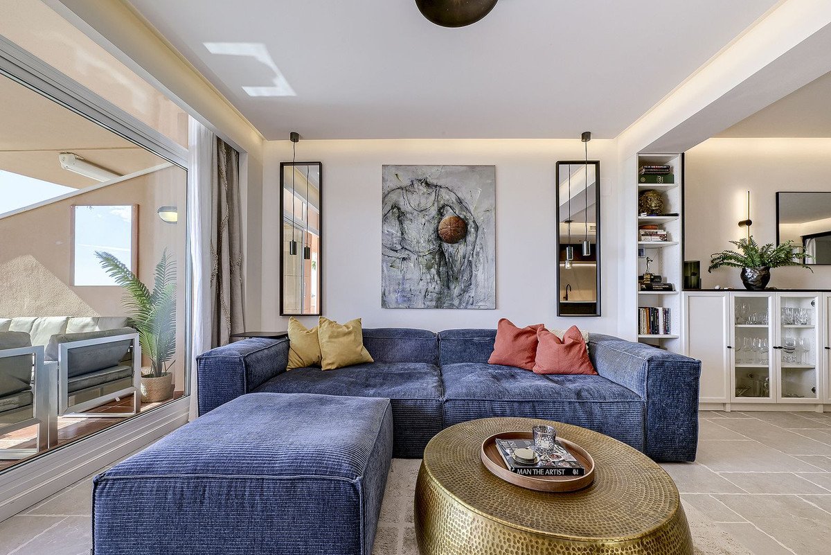 Modern living room with blue sofa, yellow and red pillows, and large windows