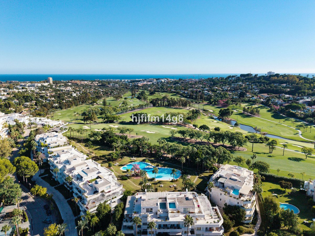 Aerial view of apartment complex with golf course, swimming pools, and ocean view