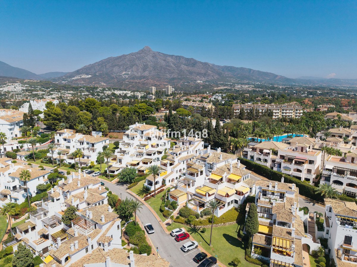 Aerial view of a residential complex with mountain backdrop and green surroundings