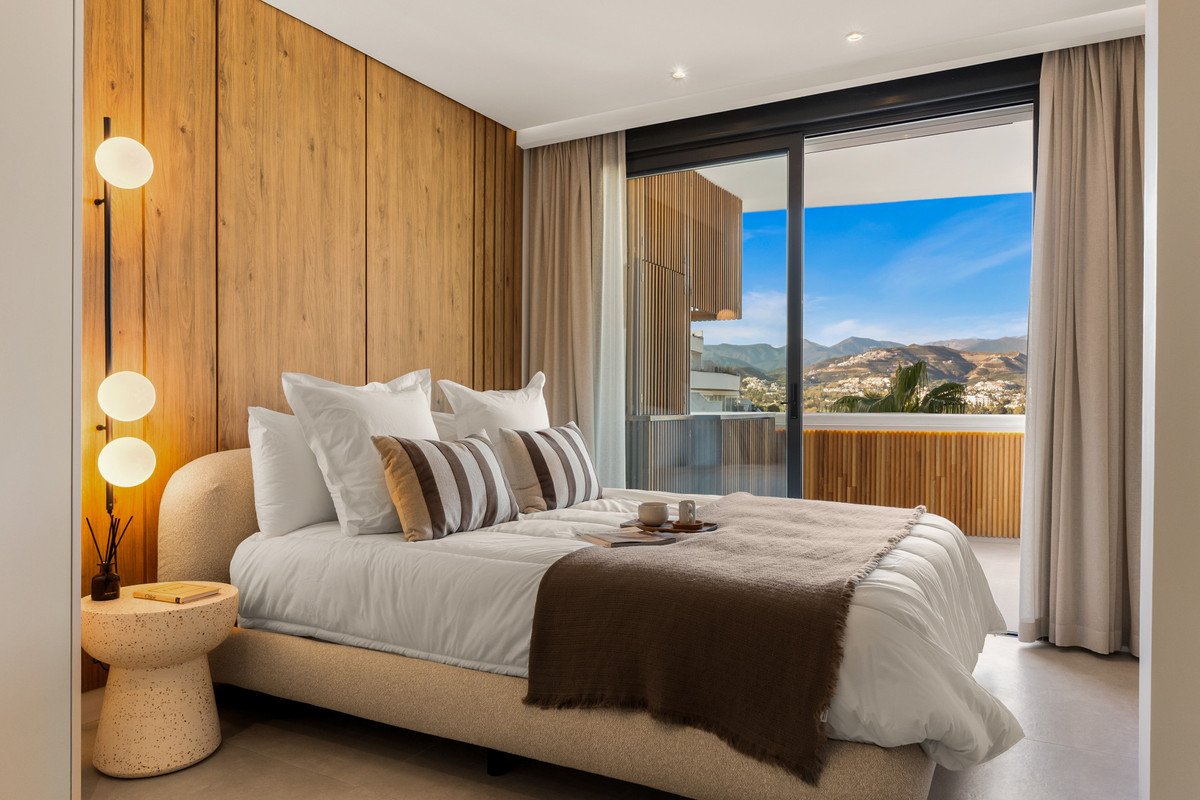 Cozy bedroom with wood accent wall, a large bed, and sliding glass doors opening to a balcony with a stunning mountain view.