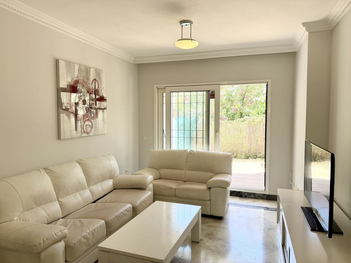 A bright living room with cream leather sofas, a coffee table, and sliding doors to a garden.
