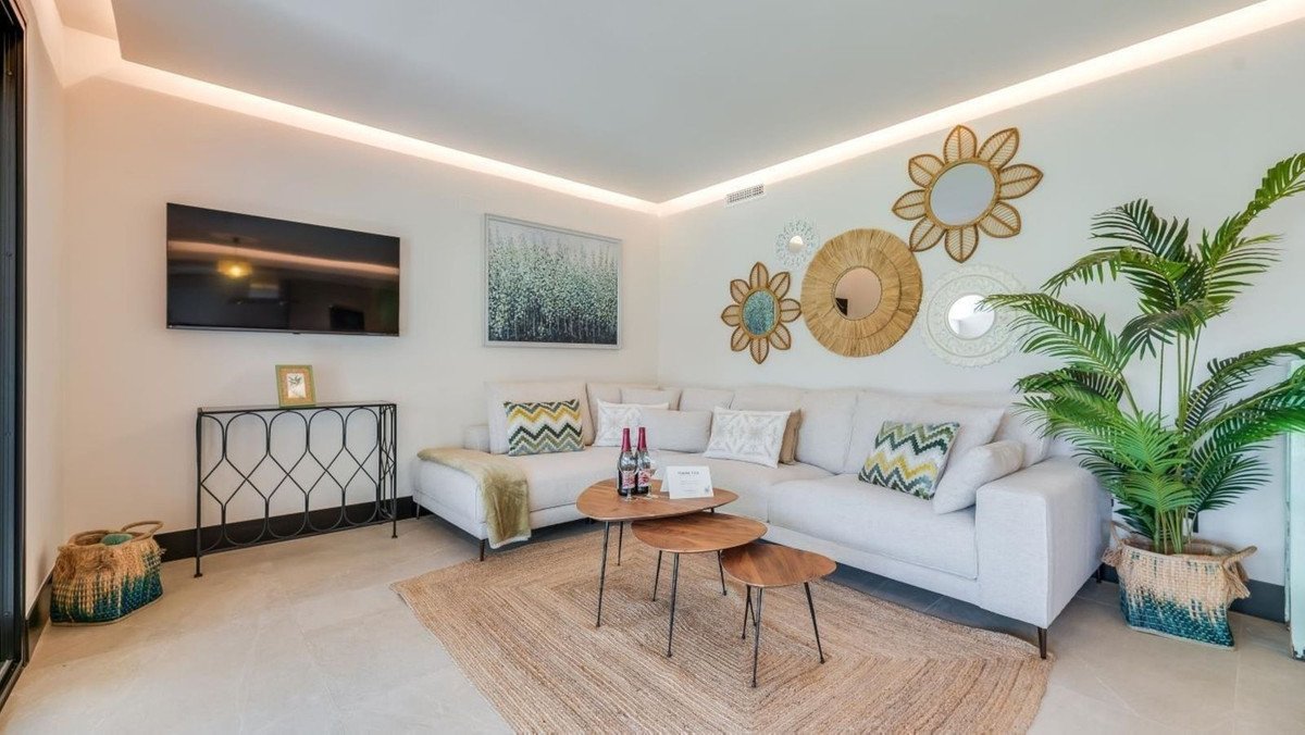 Modern living room with a large sectional sofa, coffee table, TV, and decorative mirrors on the wall.
