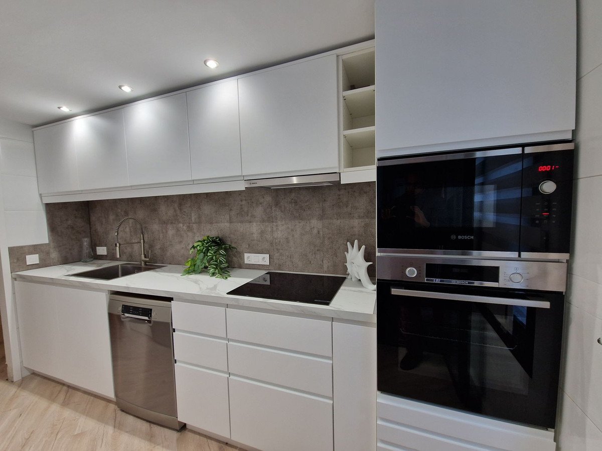 Modern kitchen with white cabinets, stainless steel appliances, and a sleek countertop.