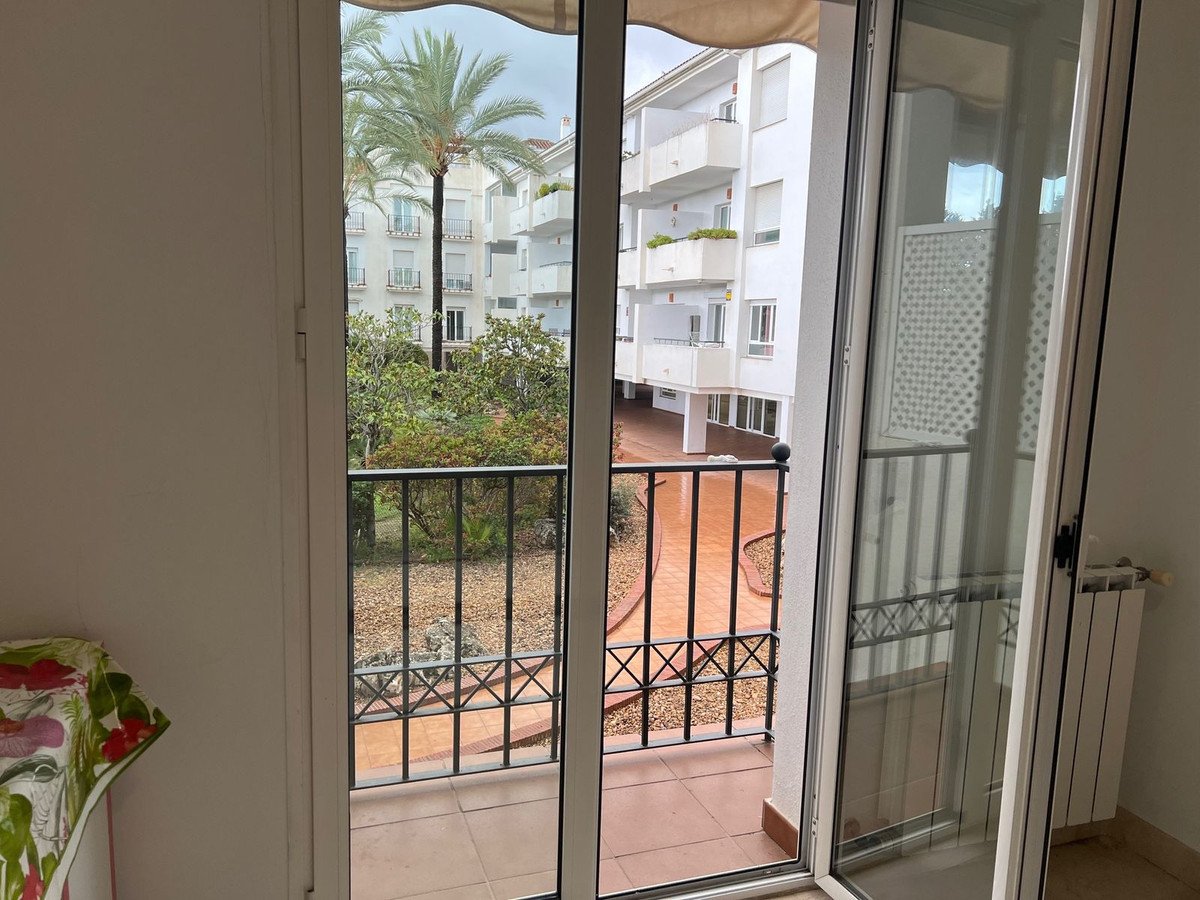 Apartment balcony with view of palm trees and neighboring buildings
