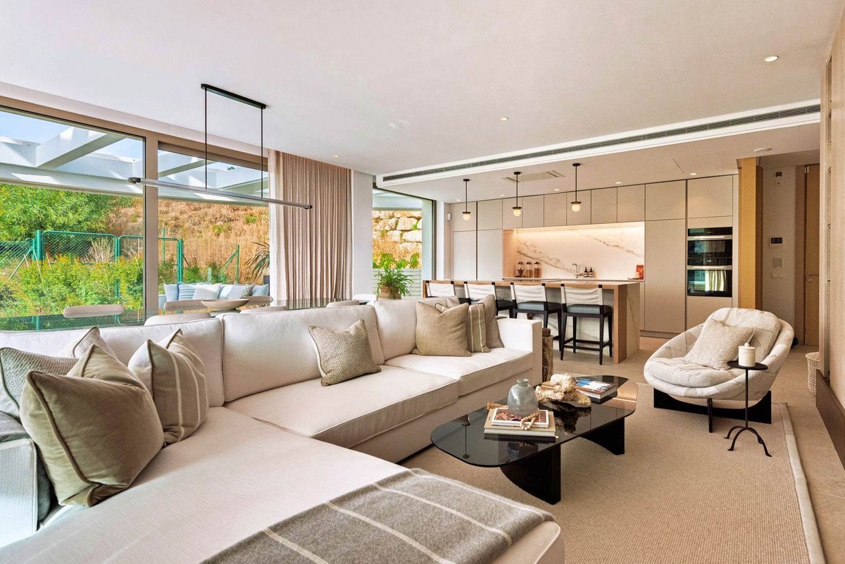 Modern living room with large windows overlooking a garden and kitchen area