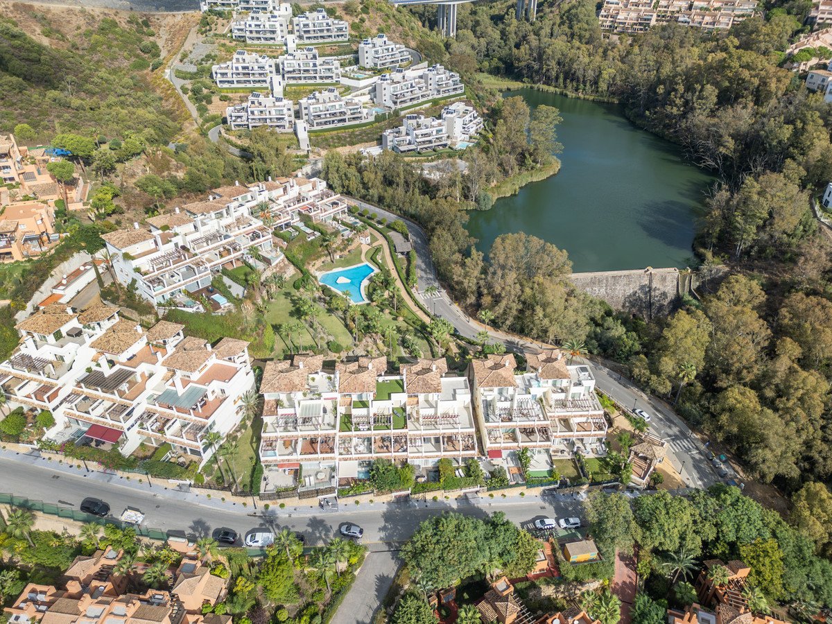 Aerial view of a residential complex with a swimming pool and a lake surrounded by lush greenery.