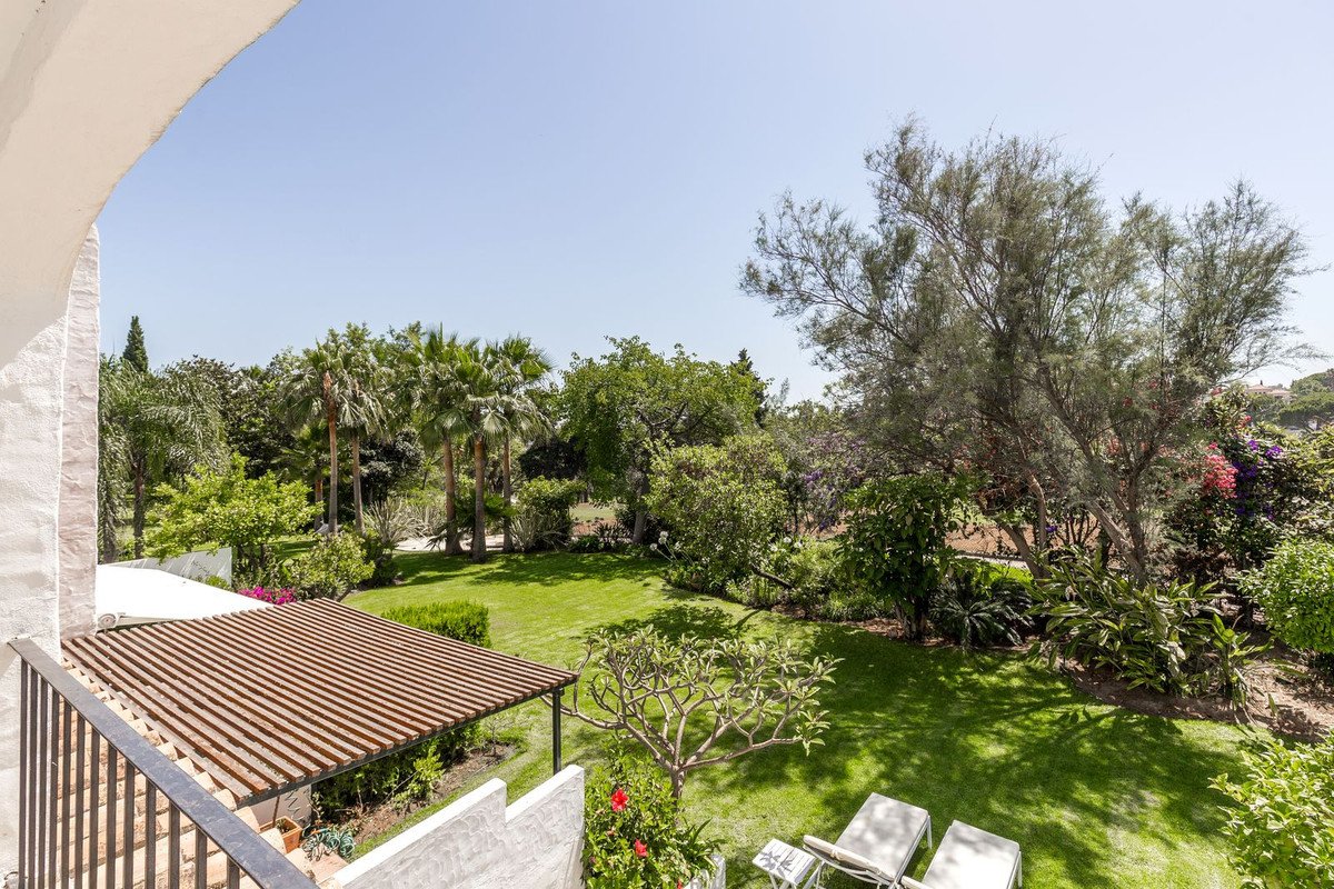 Balcony view of lush garden with palm trees and outdoor seating area