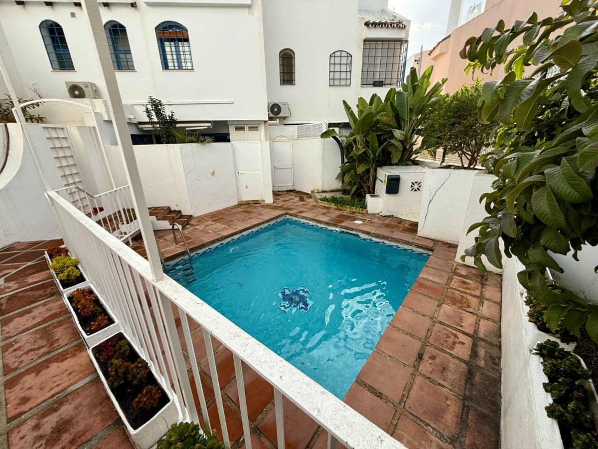 A private swimming pool with tiled surround and lush tropical plants, featuring white railings and stairs.