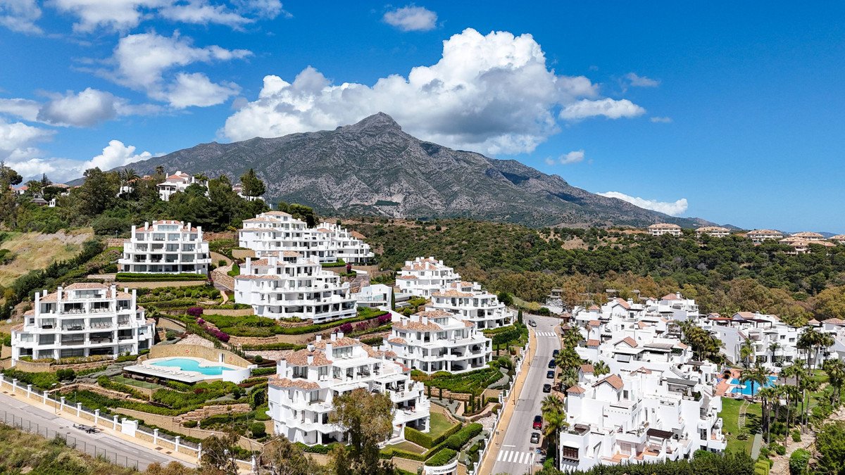 Luxury resort apartments with a swimming pool and a majestic mountain backdrop under a blue sky.
