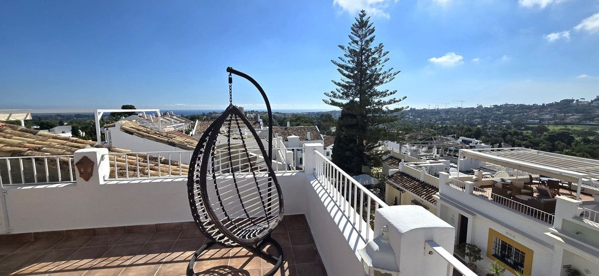 Rooftop terrace with hanging chair overlooking coastal town and sea