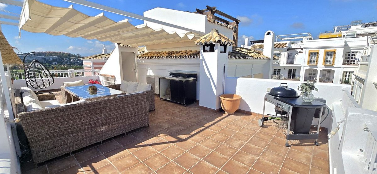 Rooftop terrace with wicker seating, barbecue, and scenic city view