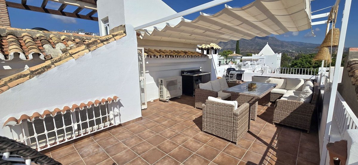 Rooftop terrace with sun shade, seating, and mountain views