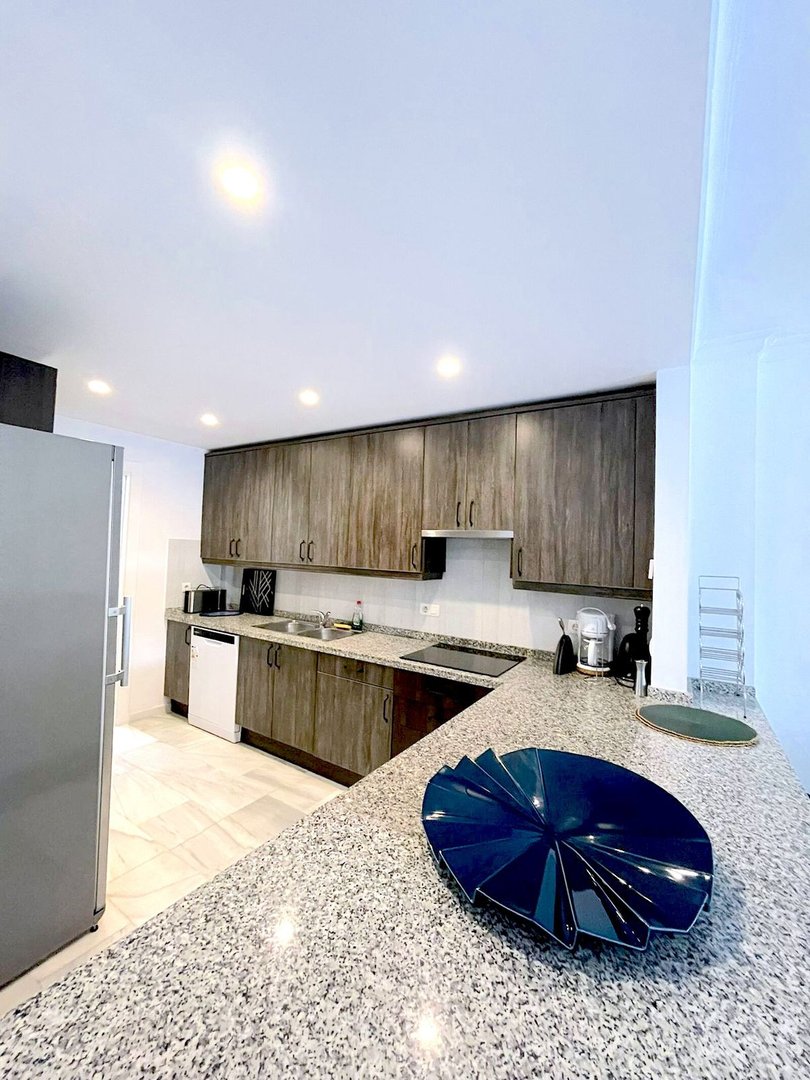 Modern kitchen with granite countertops, wooden cabinets, stainless steel appliances, and a bright, clean design-focused aesthetic.
