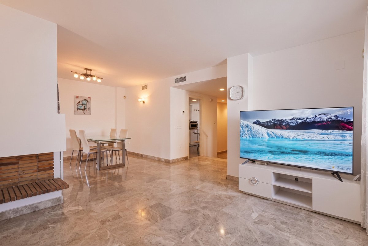 Spacious living room with marble floors, large TV, and dining area