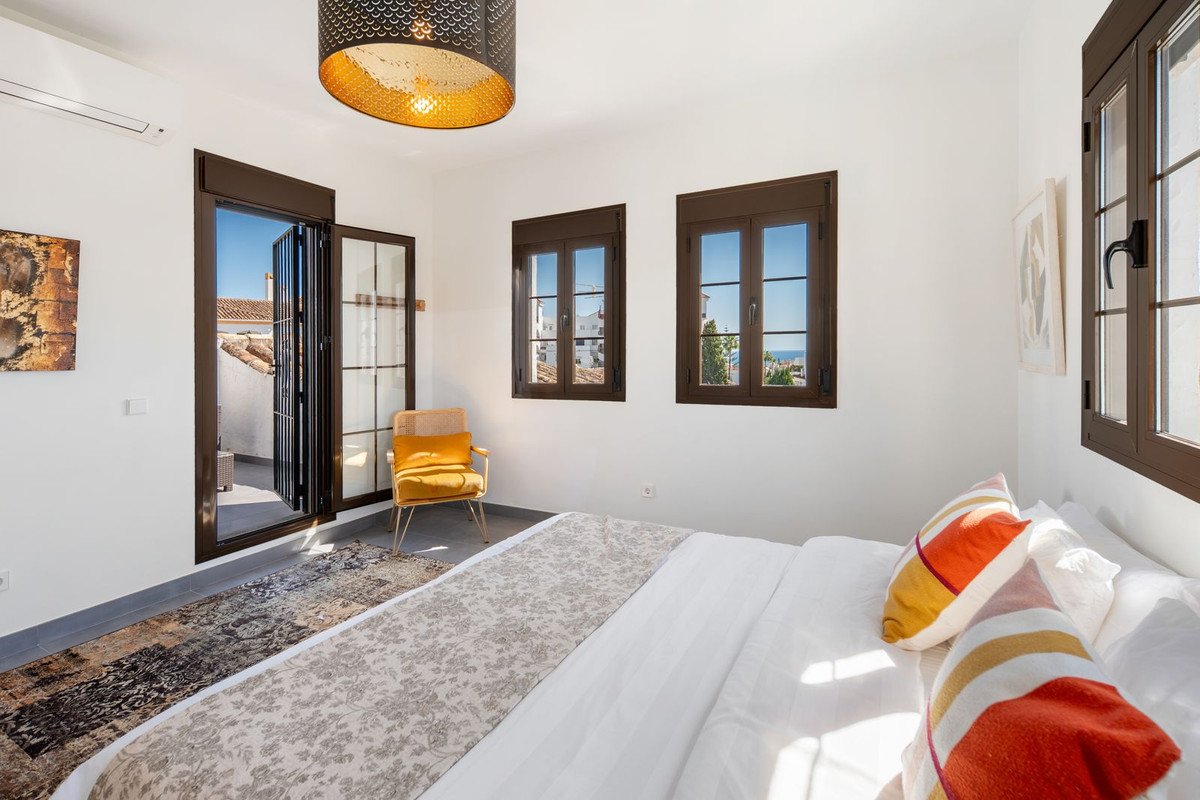 Bedroom with a bed, balcony access, chair, and windows offering a sea view.