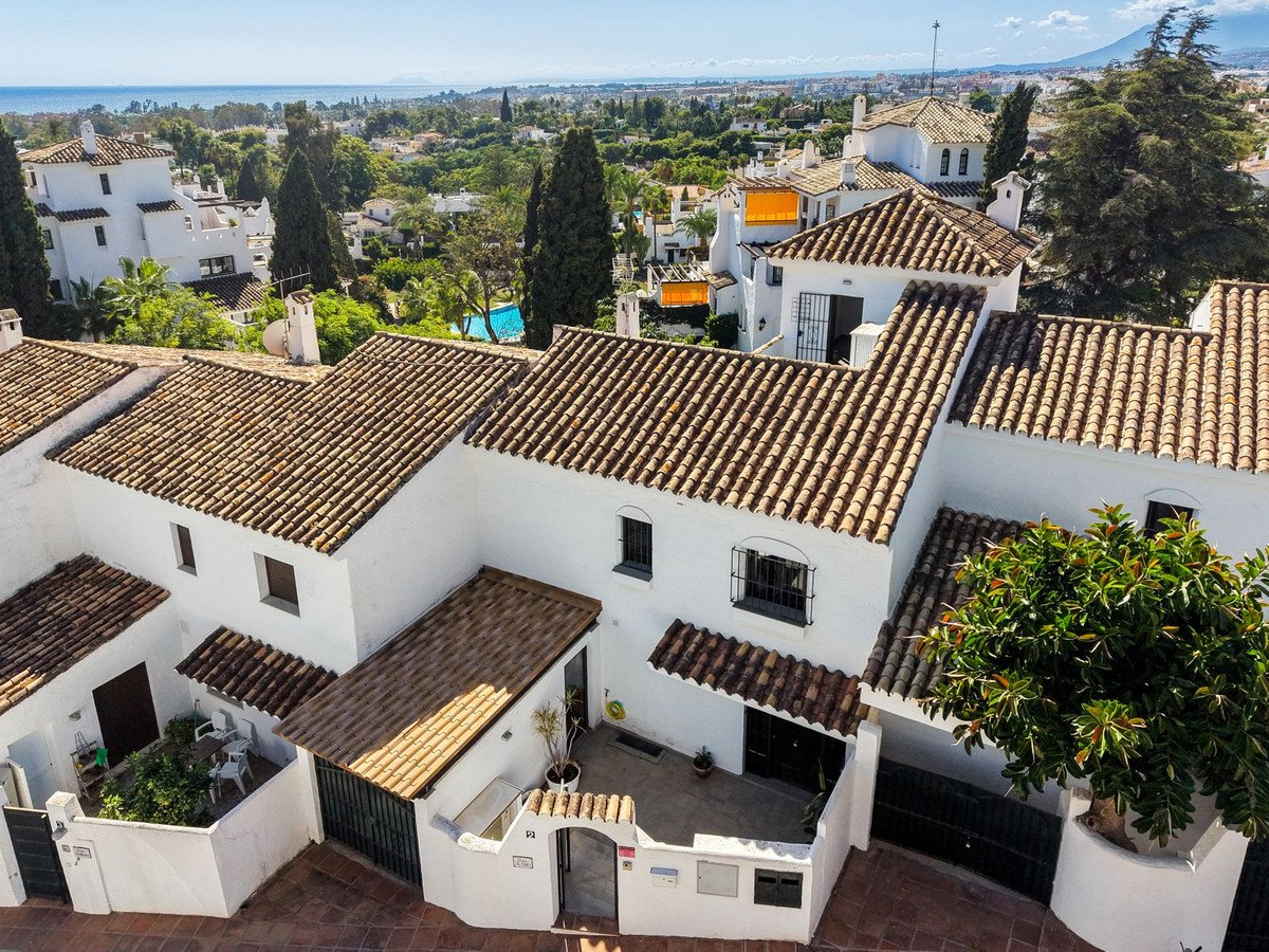 Townhouses with terracotta roofs and sea views, featuring a swimming pool and lush greenery.