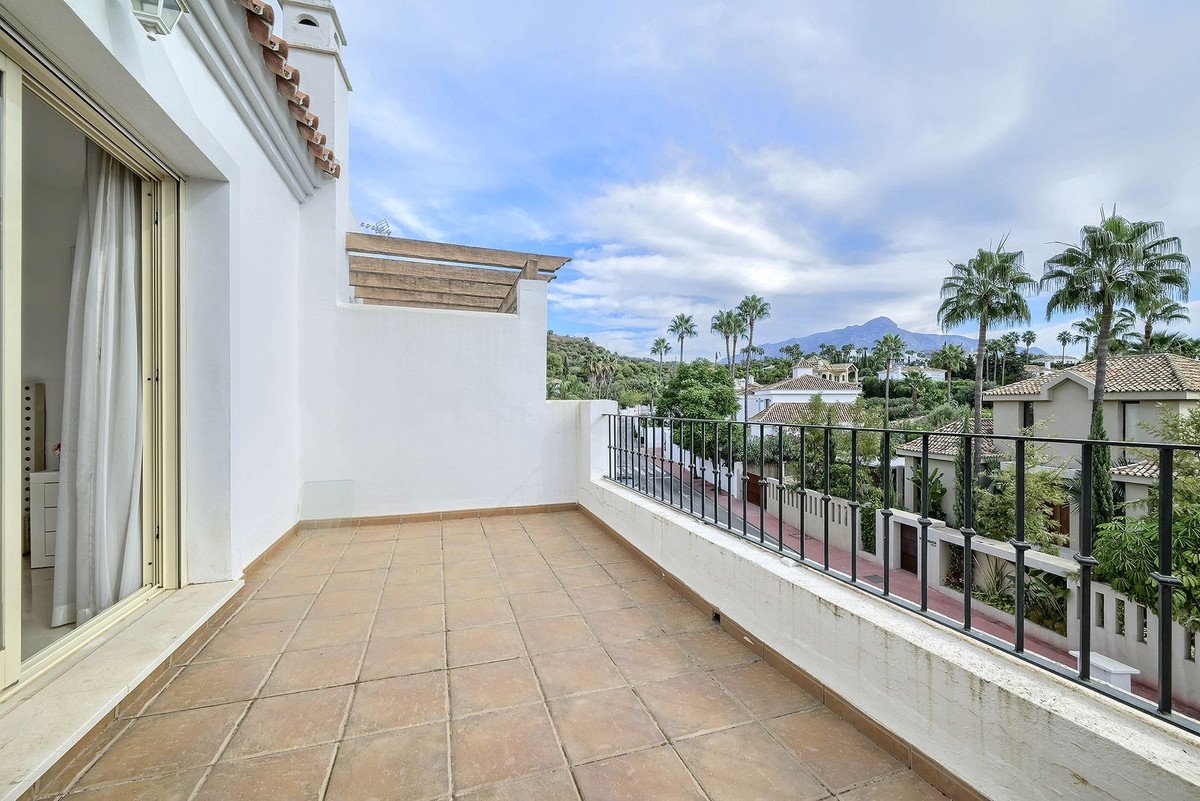 A balcony with tiled flooring and a view of mountains and palm trees.