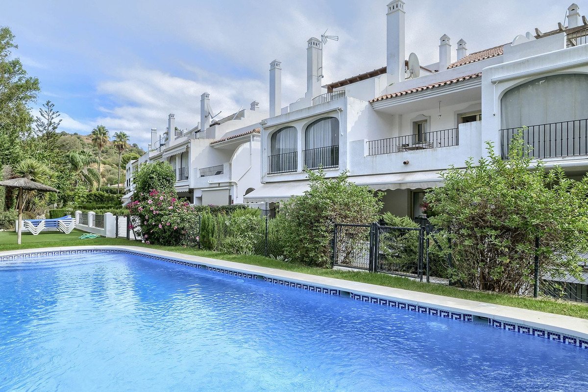 Blue swimming pool in front of white apartment buildings with greenery