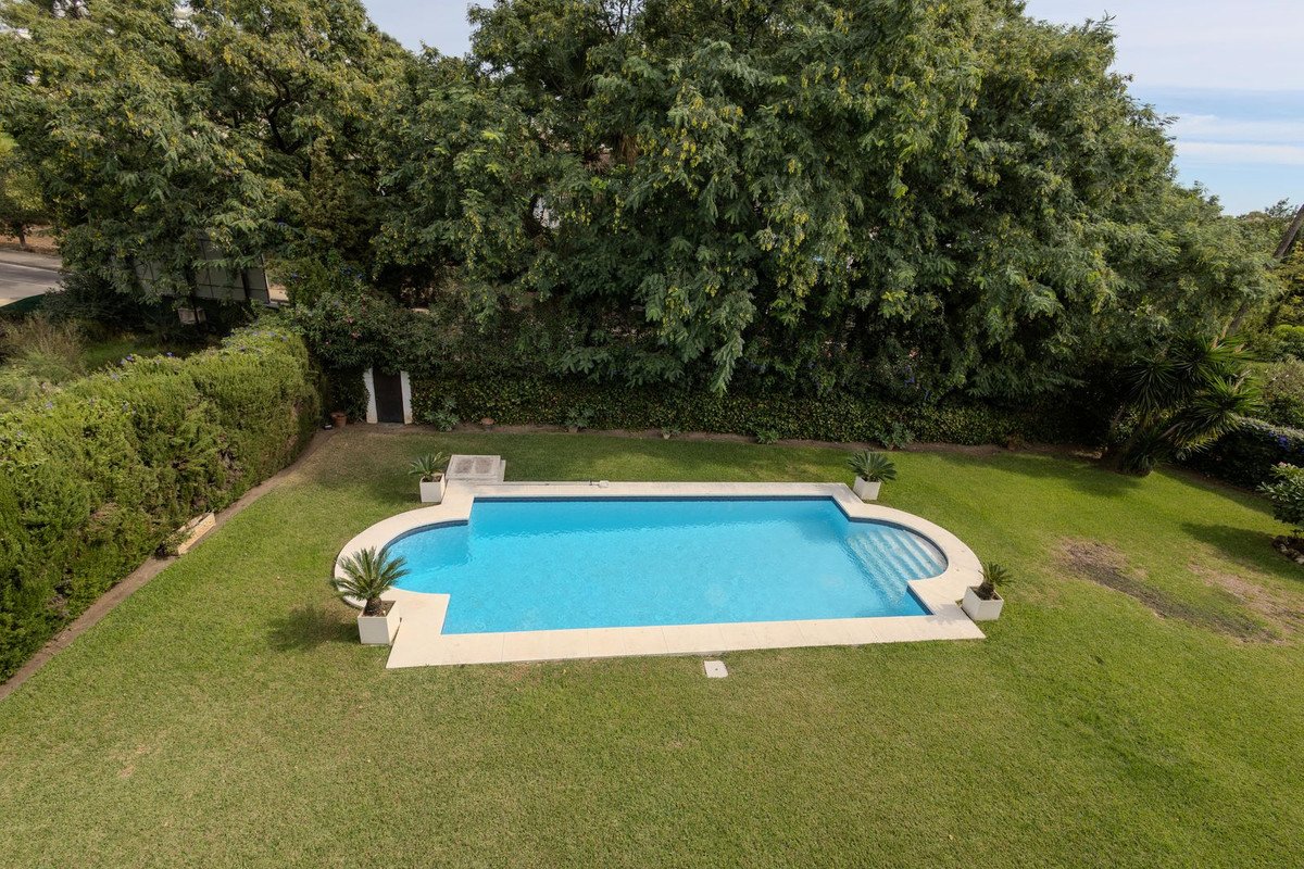 A backyard with a swimming pool surrounded by green lawn and trees.