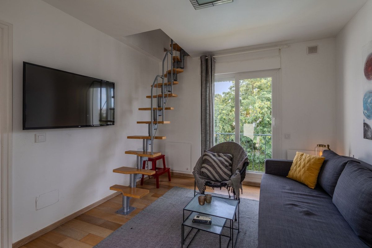 Modern living room with spiral staircase, sofa, and large window view