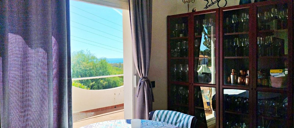 Dining room with ocean view through balcony doors and glass cabinet