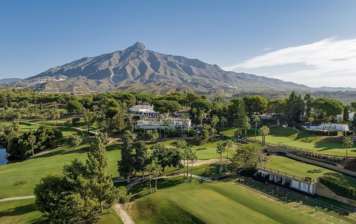 Aerial view of a villa on a golf course with mountain backdrop