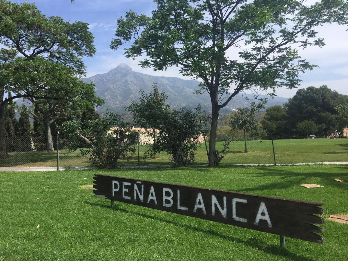 Wooden sign reading Peñablanca on a grassy golf course with mountain view