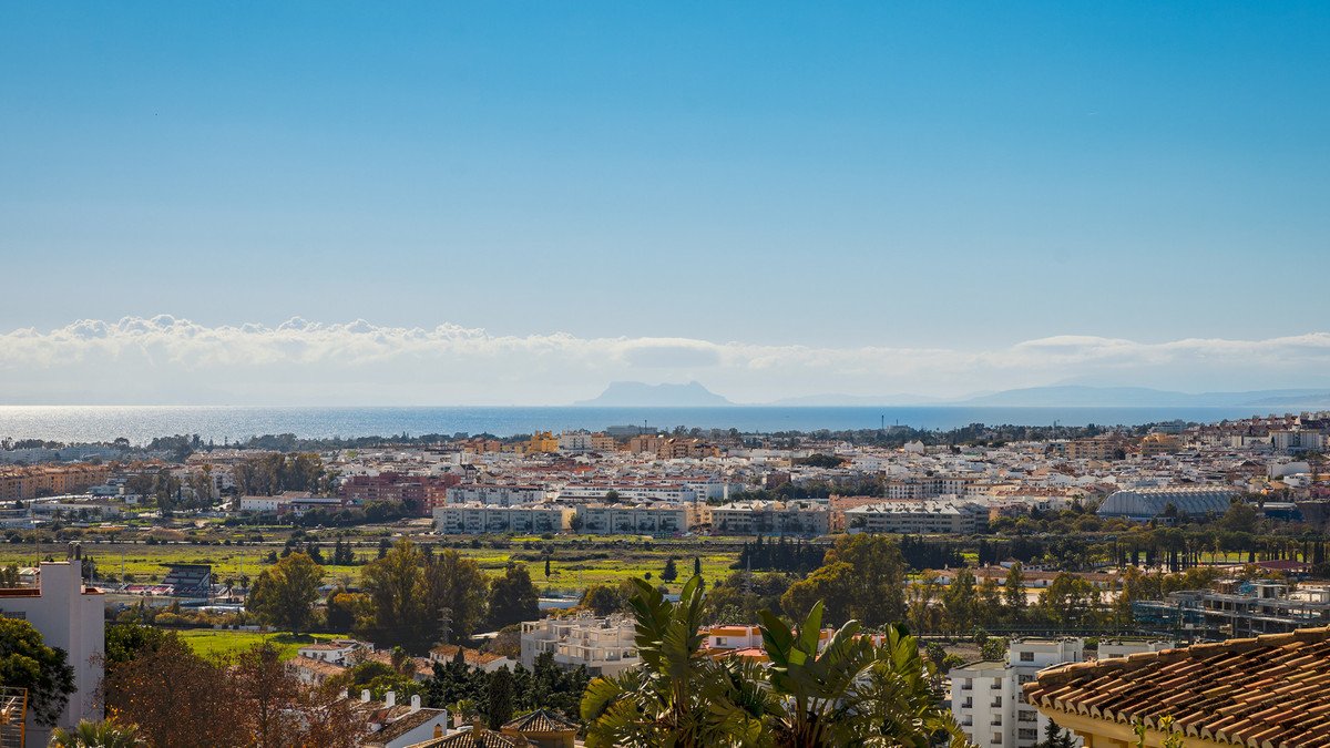 Panoramic view of a coastal town with the sea in the background and mountains on the horizon.