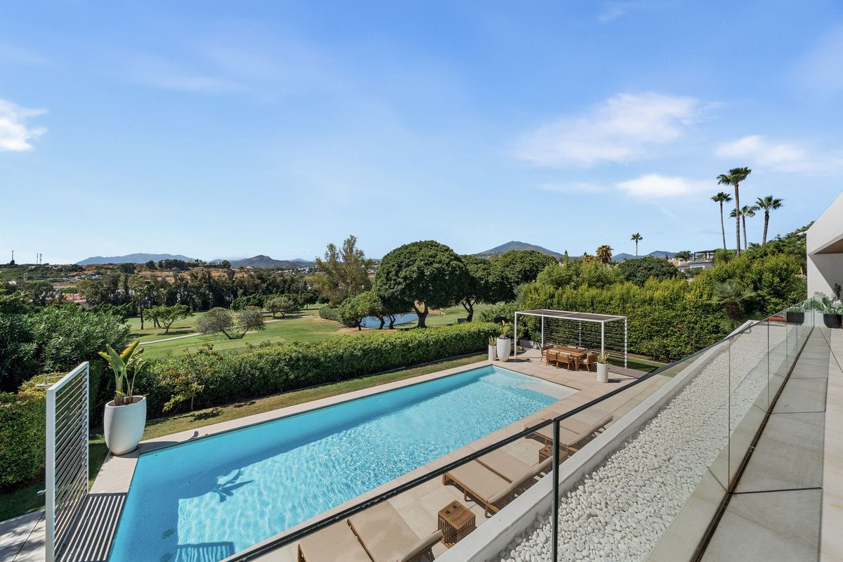 Modern outdoor pool with lounge chairs overlooking a golf course and mountains