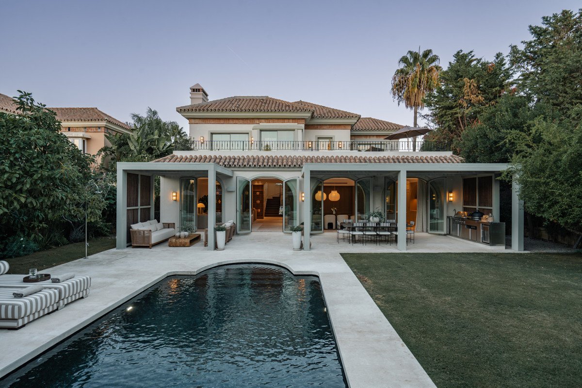 Modern house exterior with a swimming pool, outdoor seating area, dining space, and an outdoor kitchen.