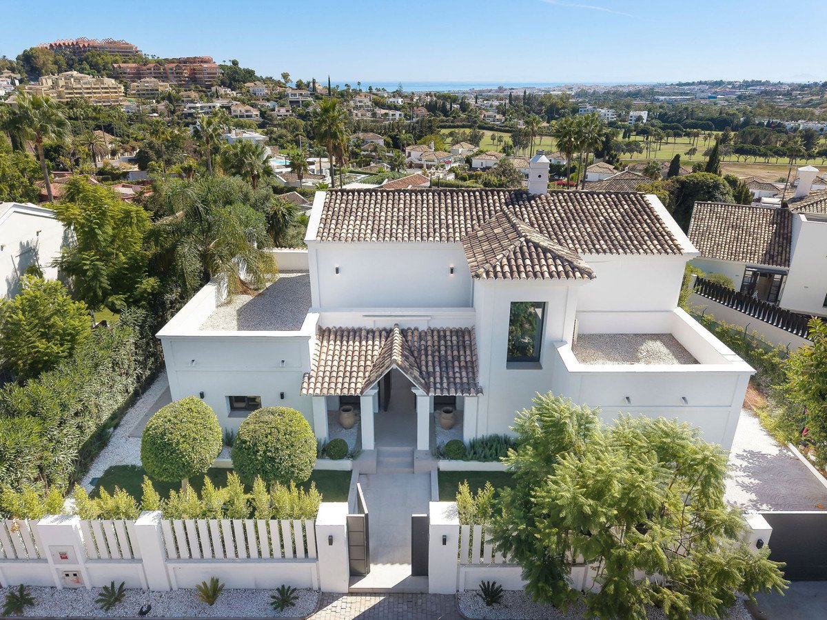 Modern white villa with tiled roof, landscaped garden, and sea view