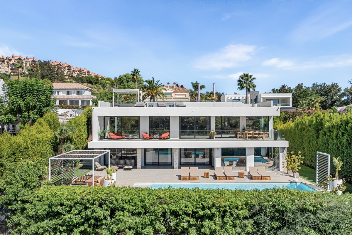 Modern villa with swimming pool, lounge chairs, outdoor dining area, and panoramic windows.