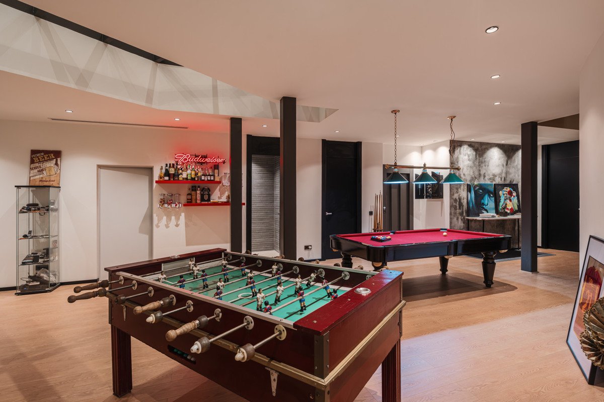 Recreation room featuring a foosball table, pool table, and a bar with Budweiser neon sign.