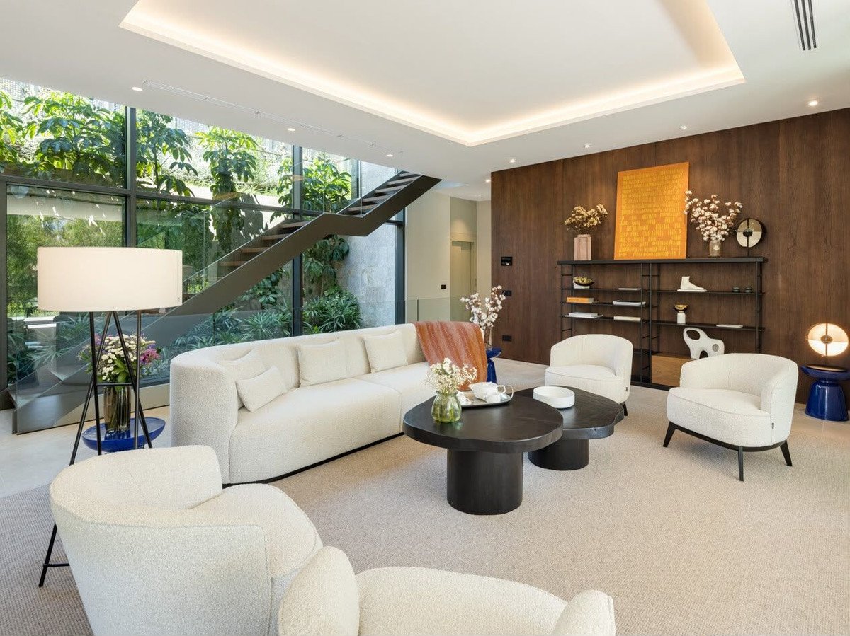 Modern living room with large windows, white sofa, and wooden accent wall