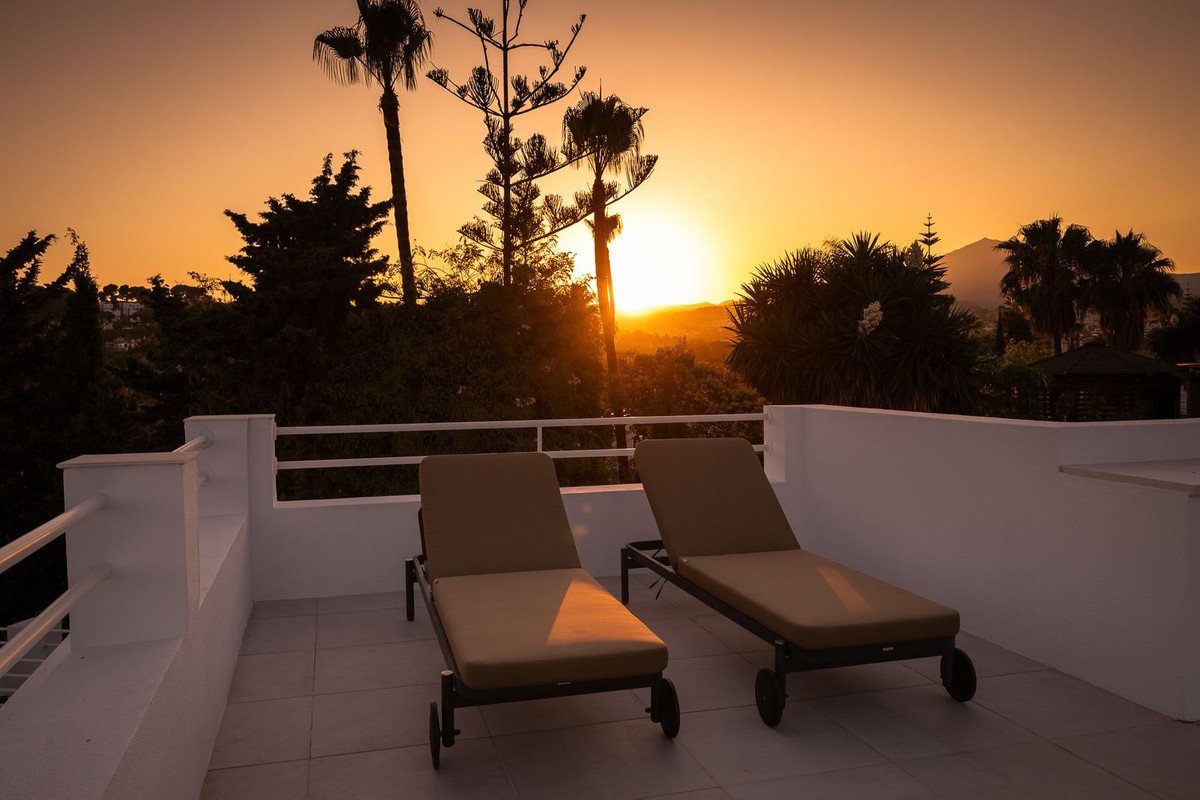 Rooftop terrace with two lounge chairs overlooking a sunset view
