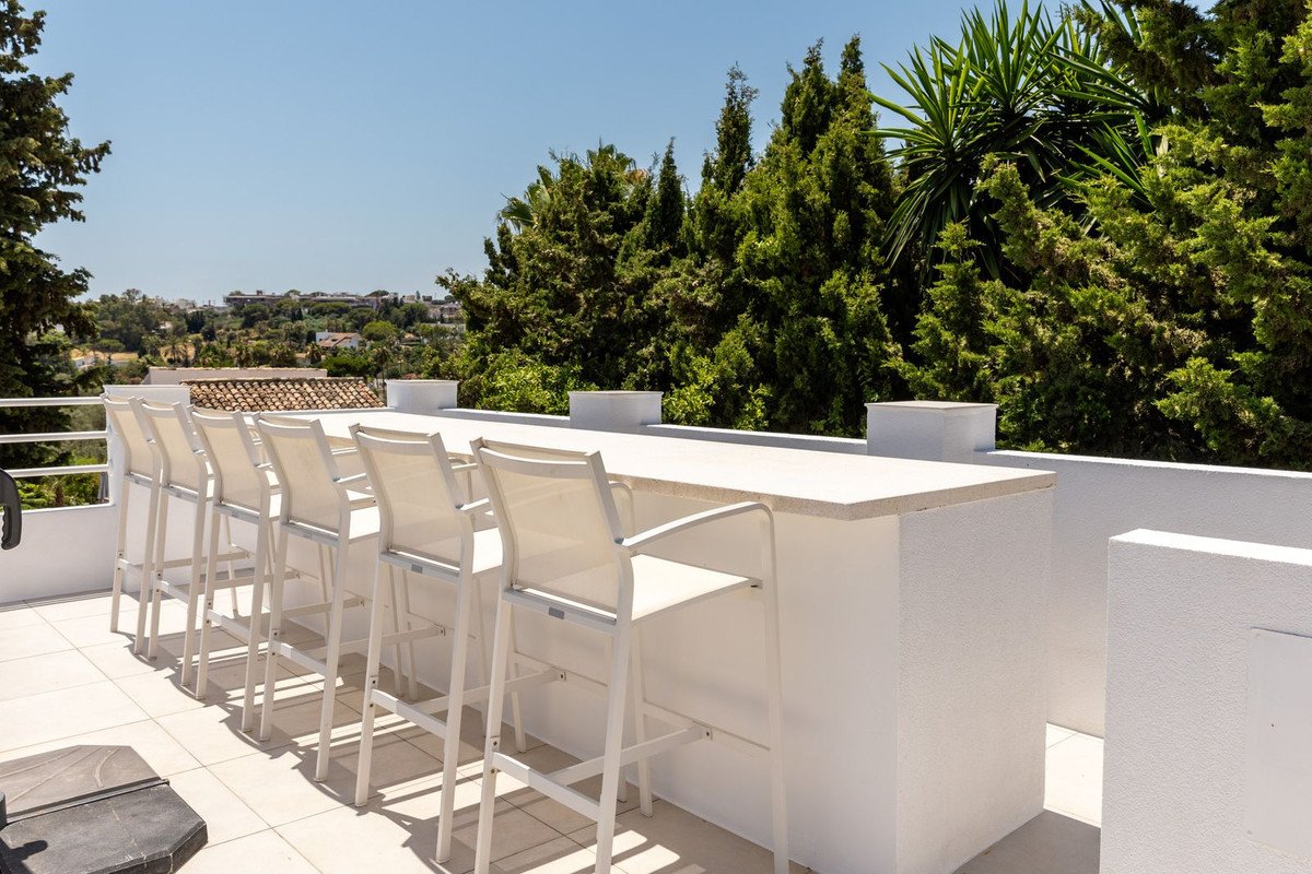 Rooftop bar with white seating and outdoor view of trees and sky
