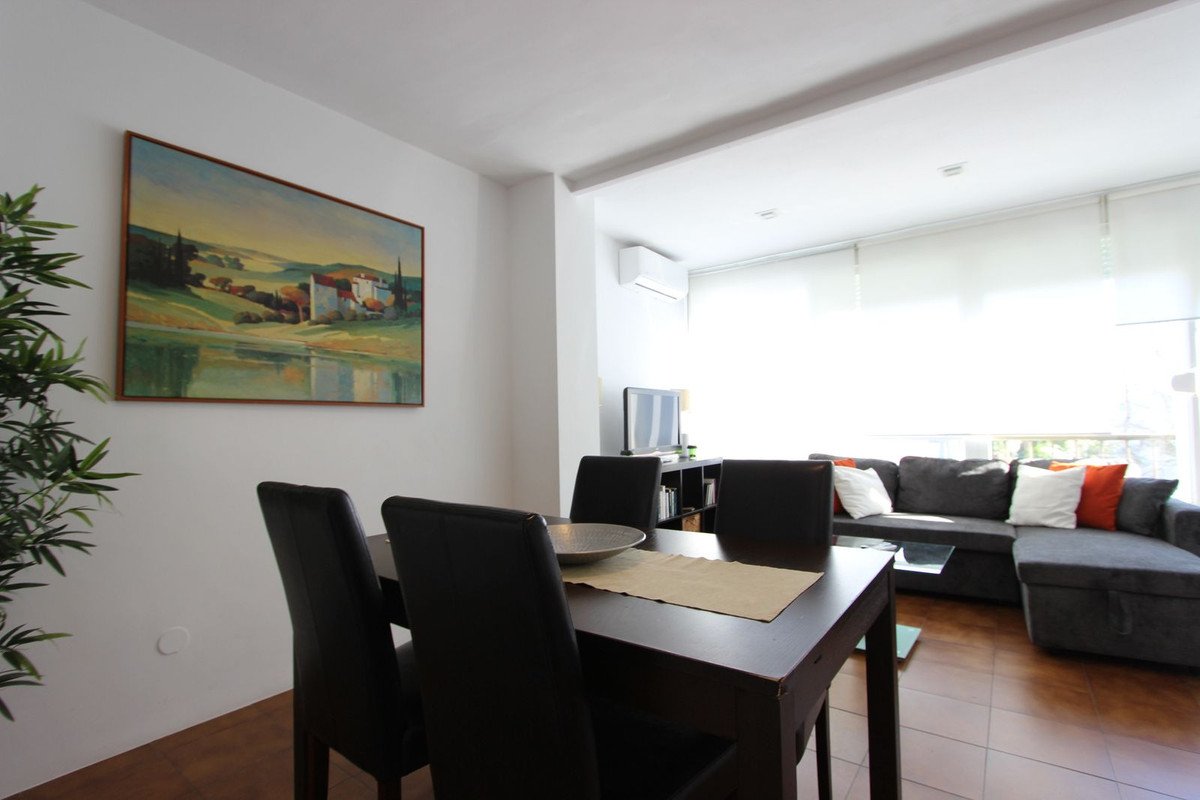 Open-plan dining and living room with sofa, dining table, and landscape painting.