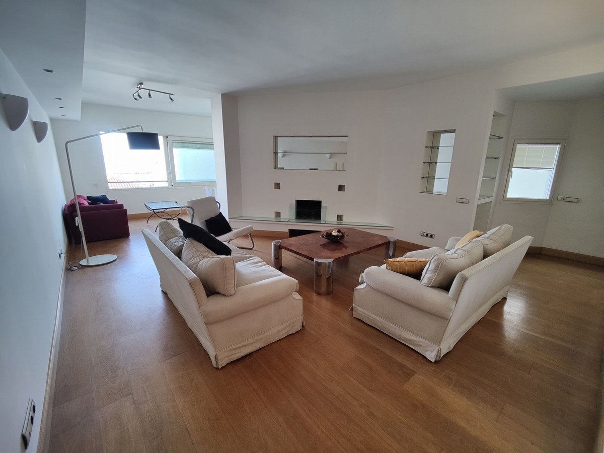 Spacious living room with two white sofas, a coffee table, a fireplace, and large windows showing natural light.