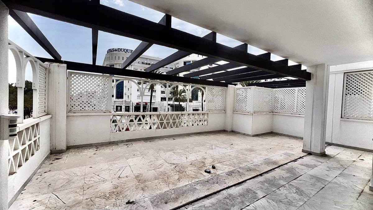 Roofed terrace with white lattice walls and distant building view