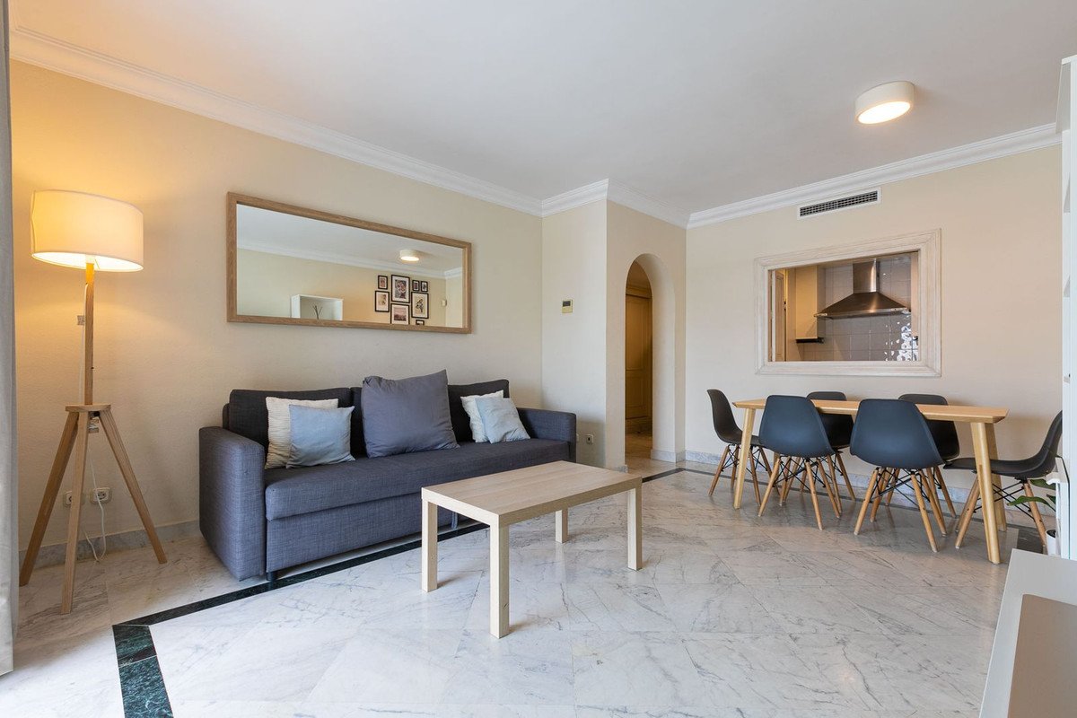 Modern living and dining area with a sofa, coffee table, dining set, and a pass-through window to the kitchen.