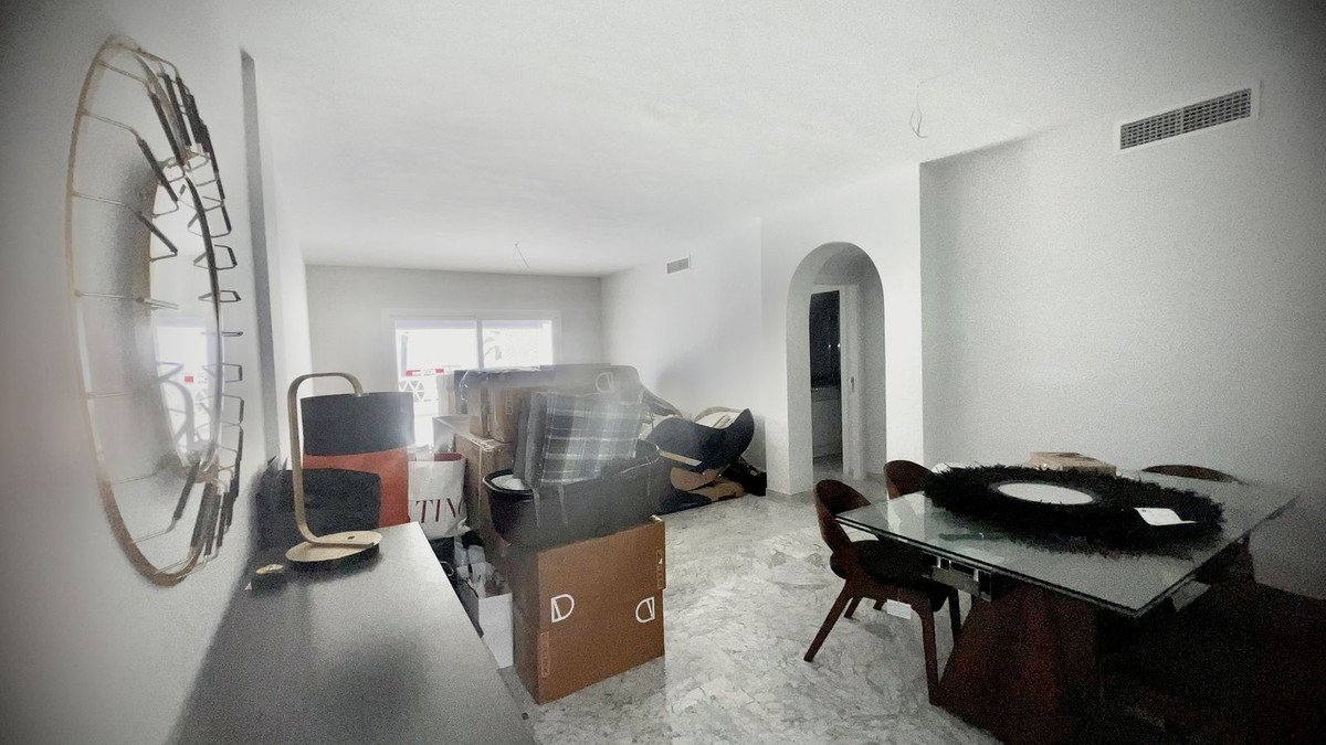 Spacious living and dining room with mirror, boxes, and glass table